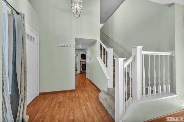 stairway featuring a fireplace, wood-type flooring, and an inviting chandelier