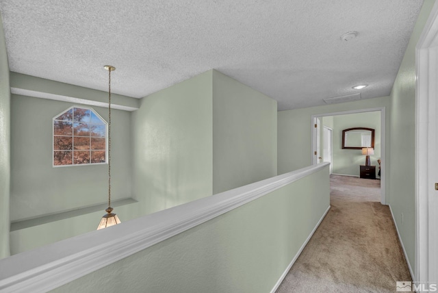 hall featuring light carpet and a textured ceiling