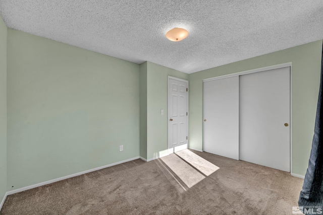 unfurnished bedroom featuring light carpet, a textured ceiling, and a closet