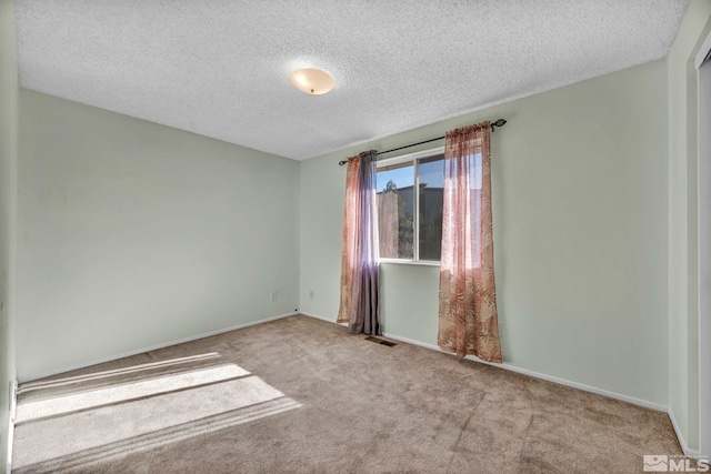 spare room featuring a textured ceiling and light colored carpet