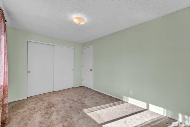 unfurnished bedroom featuring carpet floors, a textured ceiling, and a closet