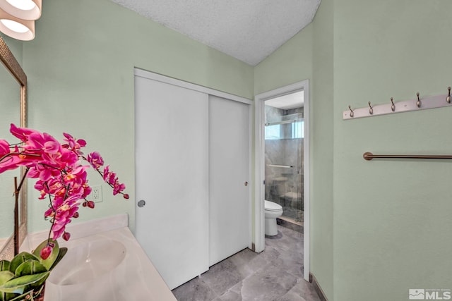 bathroom featuring vanity, toilet, a shower with shower door, and a textured ceiling