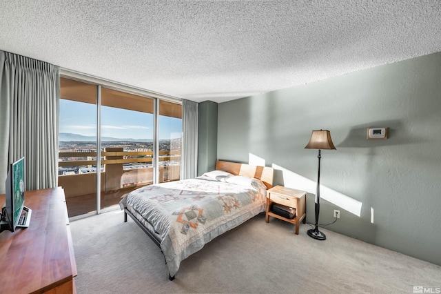 bedroom with floor to ceiling windows, a mountain view, a textured ceiling, and carpet flooring