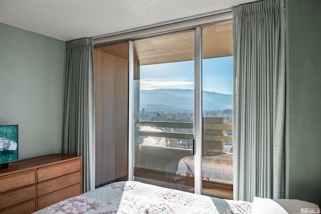 bedroom featuring a textured ceiling, floor to ceiling windows, and a mountain view