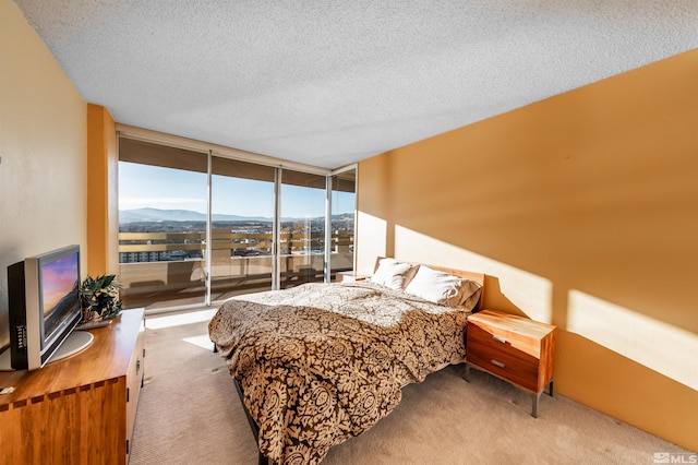 carpeted bedroom with floor to ceiling windows, a textured ceiling, and a mountain view