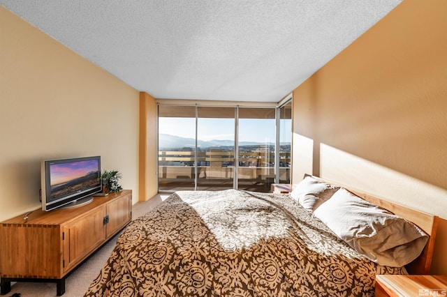 carpeted bedroom with a wall of windows, a textured ceiling, and access to outside