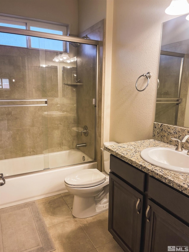 full bathroom featuring combined bath / shower with glass door, tile patterned flooring, vanity, and toilet