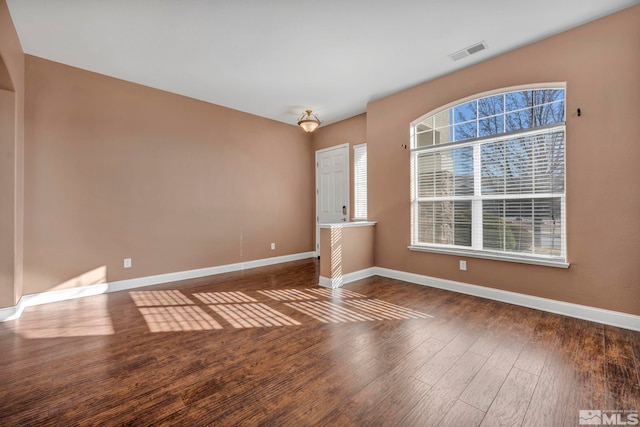 unfurnished room featuring a healthy amount of sunlight and dark hardwood / wood-style floors