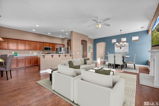 living room featuring ceiling fan with notable chandelier and dark hardwood / wood-style flooring