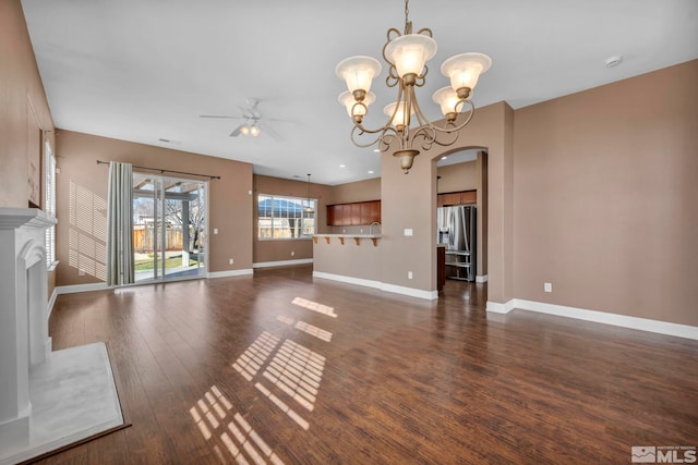 unfurnished living room with ceiling fan with notable chandelier and dark hardwood / wood-style floors