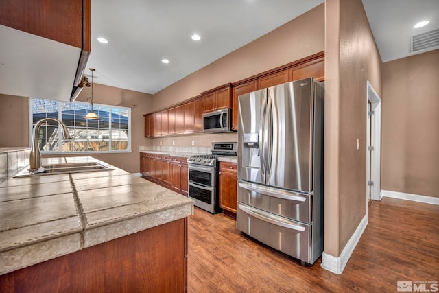 kitchen with sink, wood-type flooring, pendant lighting, and appliances with stainless steel finishes