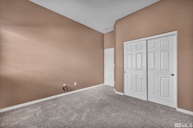 unfurnished bedroom featuring a closet, carpet floors, and vaulted ceiling