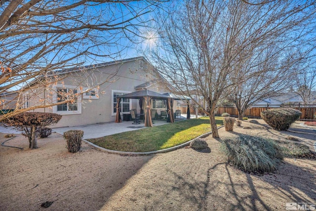 rear view of property featuring a lawn, a patio area, and a gazebo