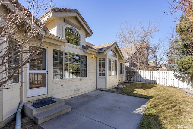 back of property with a lawn and a patio area