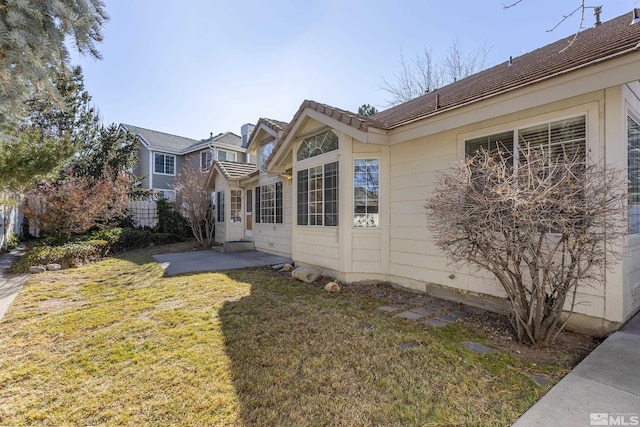 view of property exterior featuring a patio and a lawn