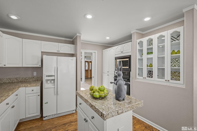 kitchen with white refrigerator with ice dispenser, black oven, a center island, built in microwave, and white cabinets