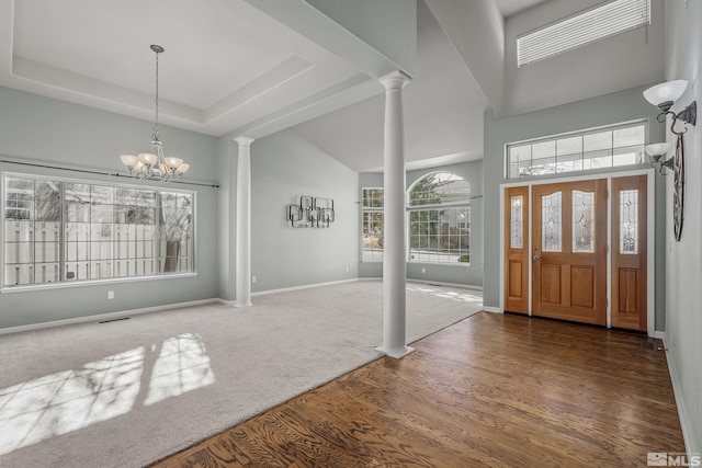 entrance foyer featuring a high ceiling, dark wood-type flooring, decorative columns, and a chandelier