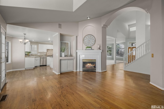 unfurnished living room with light hardwood / wood-style floors, a tile fireplace, lofted ceiling, and a chandelier