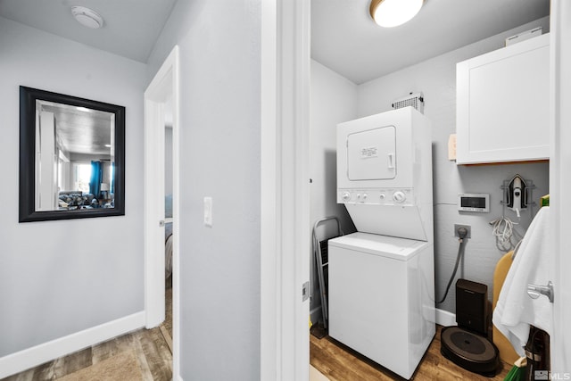 laundry area featuring light hardwood / wood-style floors and stacked washer / drying machine