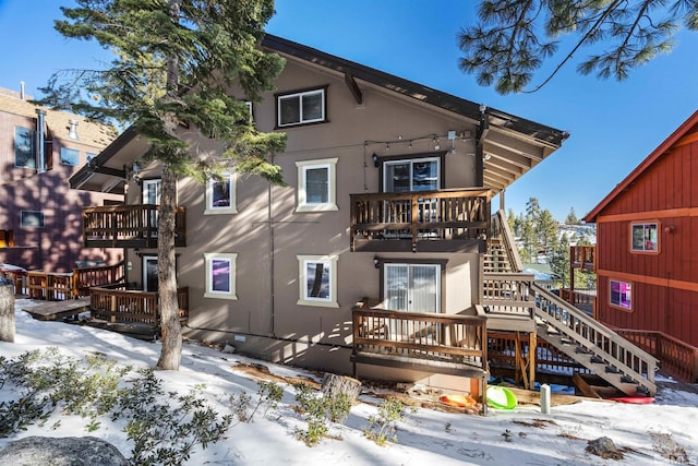 snow covered house featuring a balcony and a deck