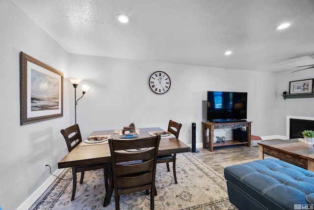 dining room with ceiling fan, light hardwood / wood-style floors, and a textured ceiling