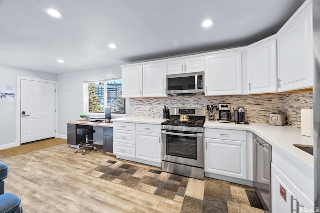 kitchen with white cabinets, stainless steel appliances, light wood-type flooring, and decorative backsplash