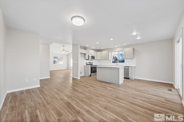 kitchen with a kitchen island, light wood-type flooring, appliances with stainless steel finishes, ceiling fan, and sink