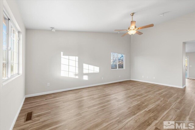 spare room featuring ceiling fan, light wood-type flooring, and a healthy amount of sunlight