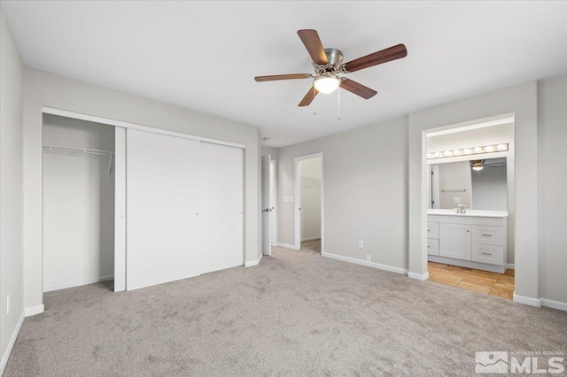 unfurnished bedroom featuring ensuite bathroom, a closet, ceiling fan, and light colored carpet