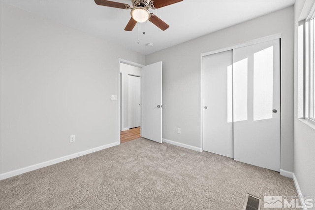 unfurnished bedroom featuring ceiling fan, a closet, and light carpet