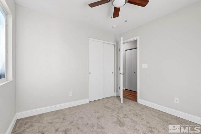 unfurnished bedroom with light colored carpet, ceiling fan, and a closet