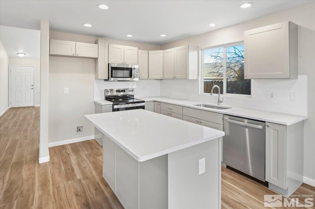 kitchen featuring stainless steel appliances, sink, a center island, light hardwood / wood-style flooring, and gray cabinets