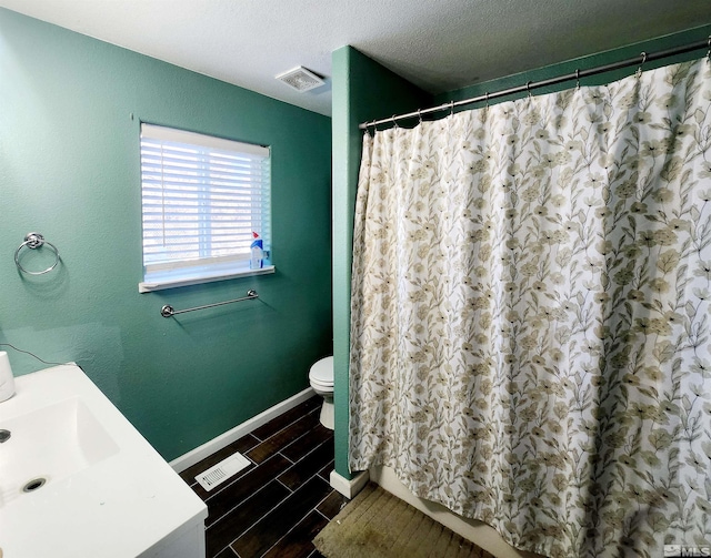 bathroom with curtained shower, toilet, and a textured ceiling