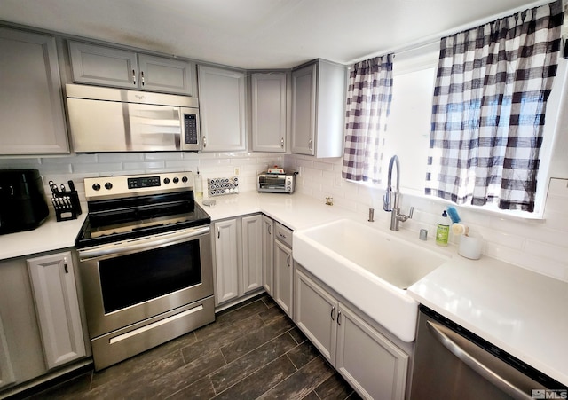 kitchen featuring sink, stainless steel appliances, gray cabinets, and tasteful backsplash