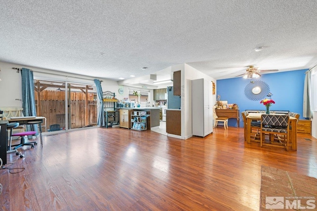 living room with a textured ceiling, ceiling fan, and light hardwood / wood-style floors