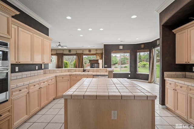 kitchen featuring light tile patterned floors, a center island, ceiling fan, and tile countertops