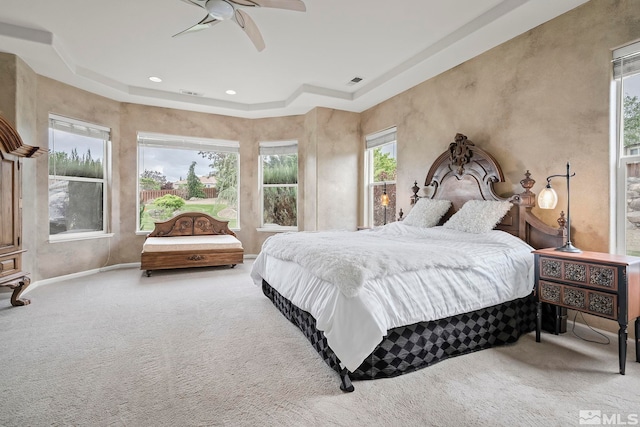 bedroom with carpet floors, ceiling fan, and a tray ceiling