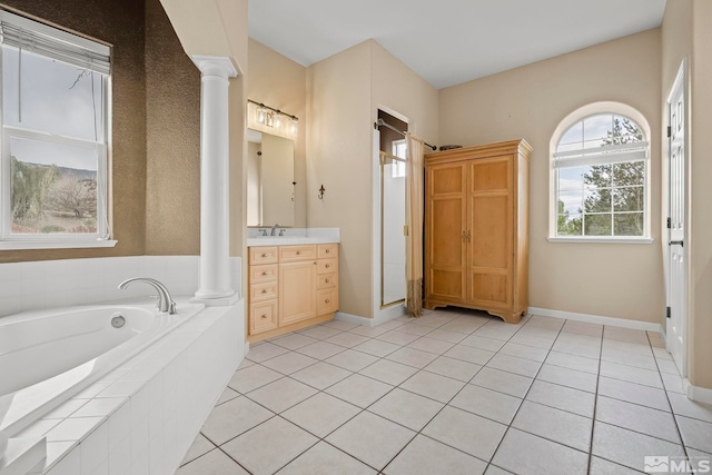 bathroom featuring ornate columns, tile patterned flooring, vanity, and a relaxing tiled tub