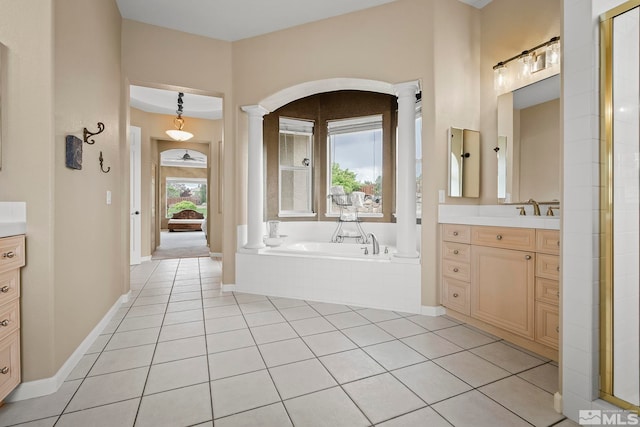 bathroom with tiled bath, vanity, tile patterned floors, and ornate columns