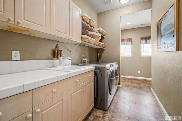 laundry room with cabinets, washing machine and clothes dryer, and sink