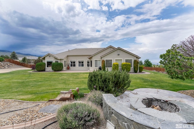 ranch-style home with an outdoor fire pit, a patio area, a front yard, and a mountain view