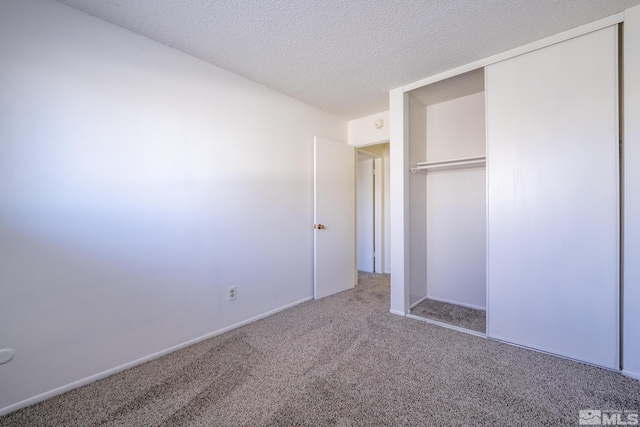 unfurnished bedroom with a textured ceiling, carpet floors, and a closet