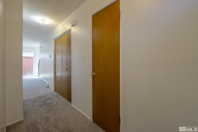 hall with a textured ceiling, carpet flooring, and a baseboard heating unit