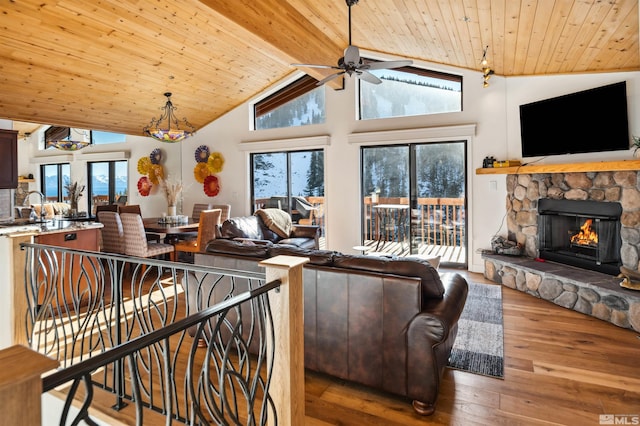 living room with wooden ceiling, hardwood / wood-style floors, ceiling fan, and a stone fireplace