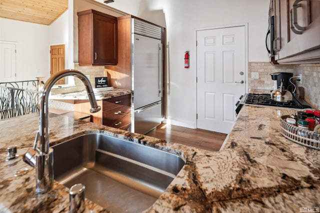 kitchen featuring stone counters, backsplash, wood ceiling, and sink