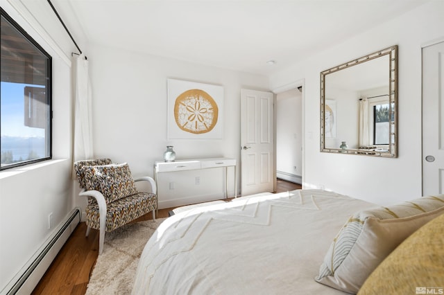 bedroom with baseboard heating and hardwood / wood-style floors