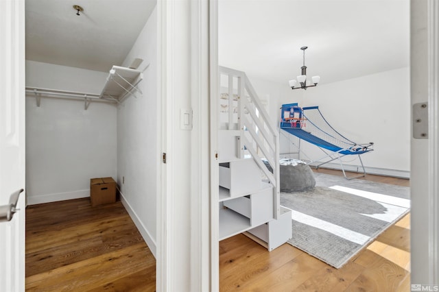 walk in closet featuring an inviting chandelier and wood-type flooring