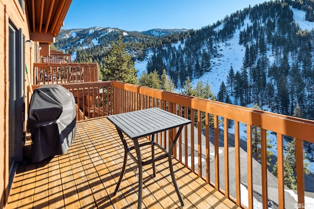 snow covered deck with a grill and a mountain view