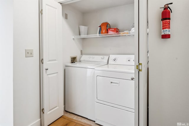 laundry area with separate washer and dryer and light wood-type flooring