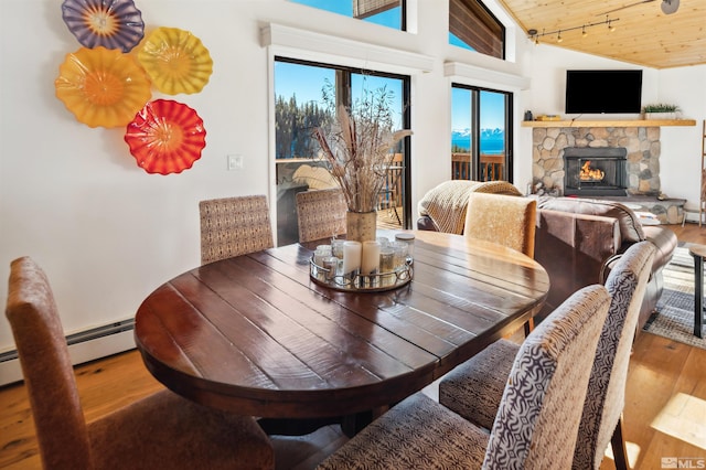 dining area featuring a fireplace, hardwood / wood-style floors, vaulted ceiling, and wood ceiling